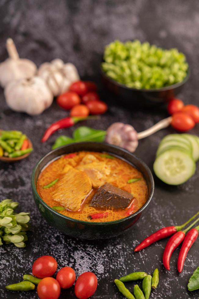 pollo al curry in una tazza nera con aglio e peperoni foto