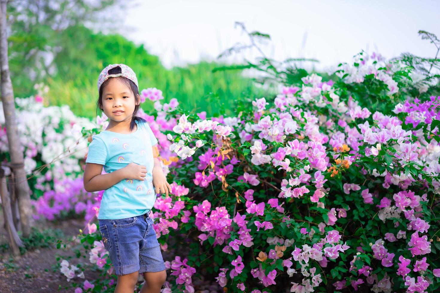 bambina asiatica che indossa un berretto con fiori di bouganville nel parco foto