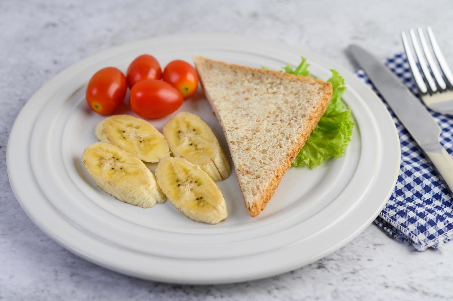 pane con banana e pomodori su un piatto bianco foto