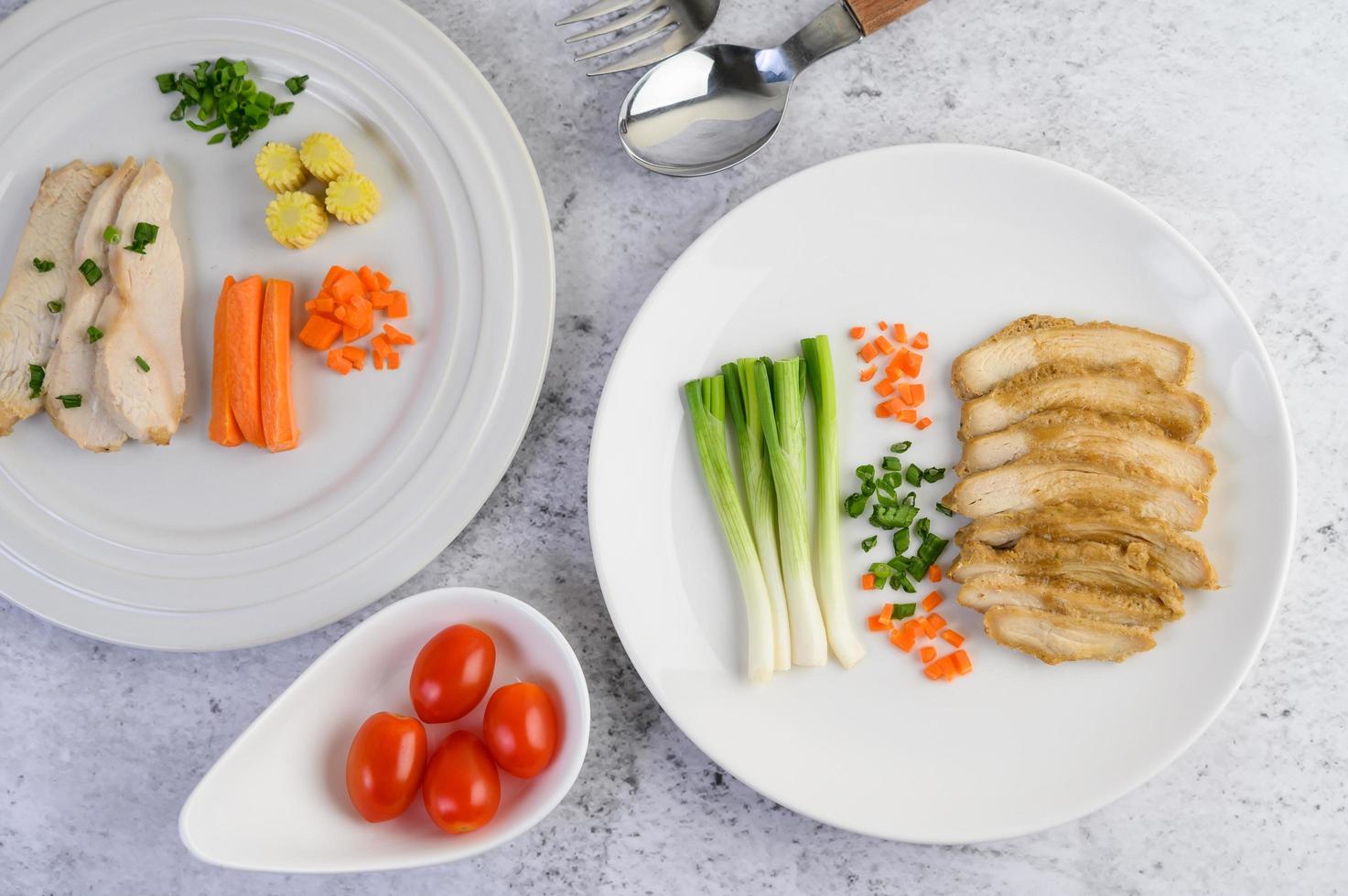 petto di pollo al vapore su un piatto bianco con cipolline e carote foto