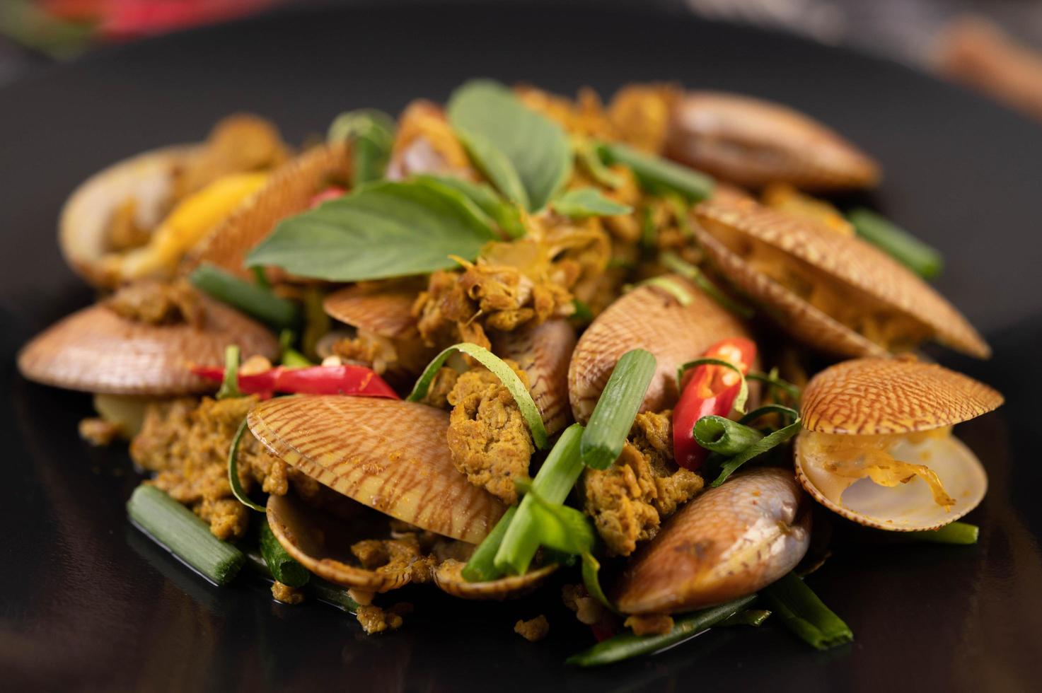 vongole fritte con curry in polvere su un piatto nero foto