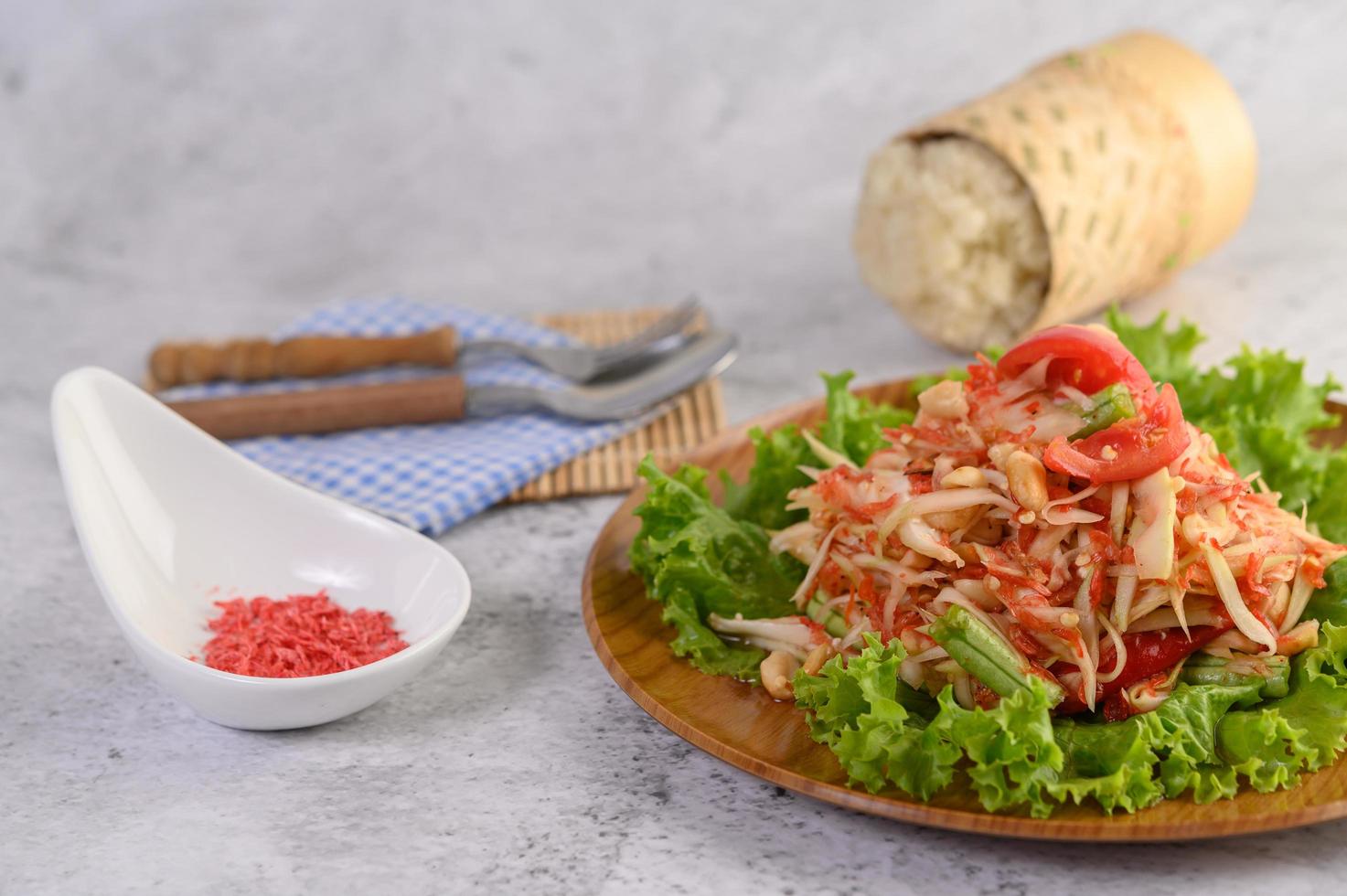 insalata di papaya su un piatto di legno con riso appiccicoso e gamberetti secchi foto