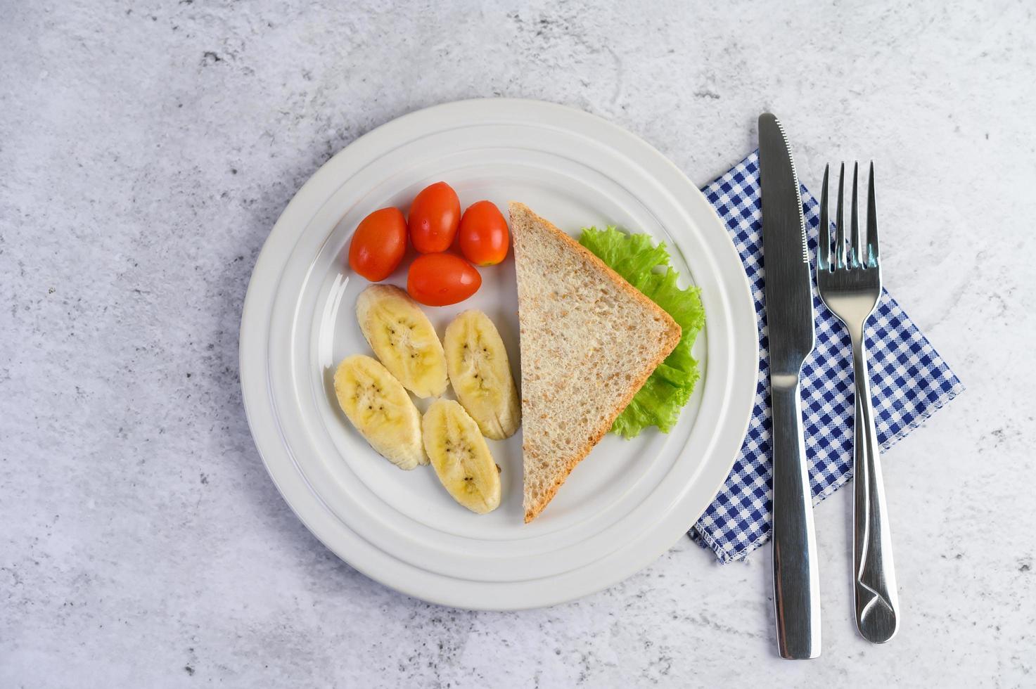 pane con banana e pomodori su un piatto bianco foto