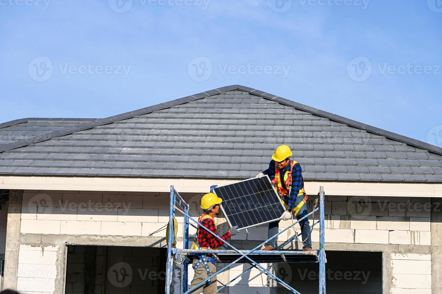 un' squadra di asiatico tecnici installa solare pannelli su il tetto di un' Casa. sezione trasversale Visualizza di costruttore nel casco installazione solare pannello sistema concetto di rinnovabile energia foto