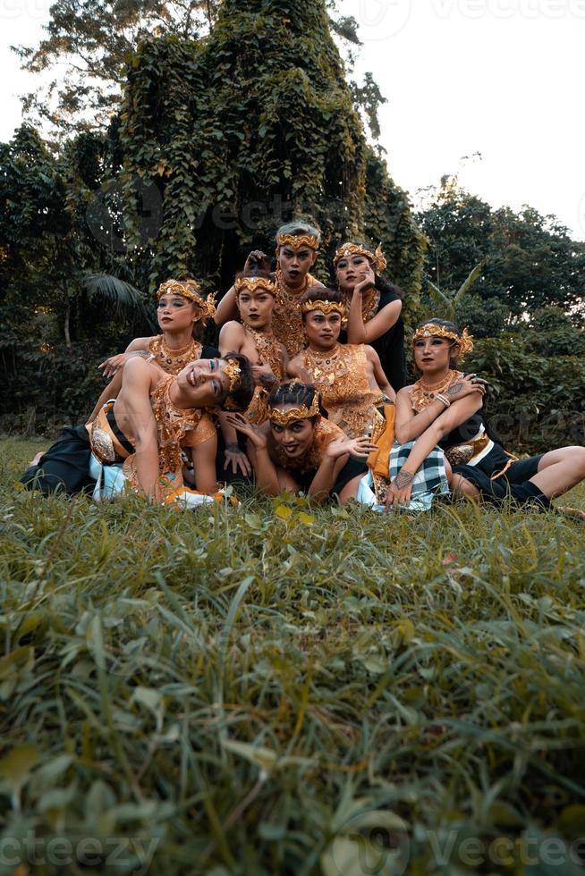 giavanese persone con tradizionale danza costumi posa giù su il erba insieme durante il foto sparare