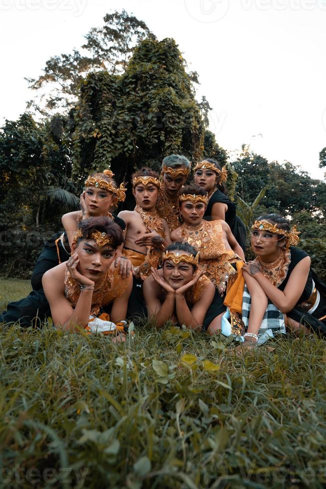 giavanese persone con tradizionale danza costumi posa giù su il erba insieme durante il foto sparare