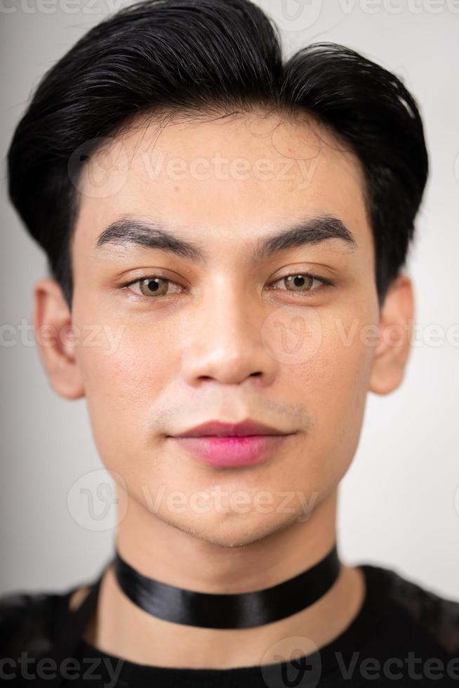 asiatico uomo con un' bella viso indossare un' nero costume mentre in posa dentro il bianca camera foto