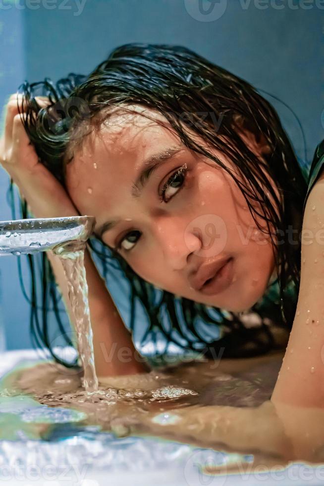 caldo femmina posa su superiore di il acqua con bagnato capelli e bagnato corpo foto