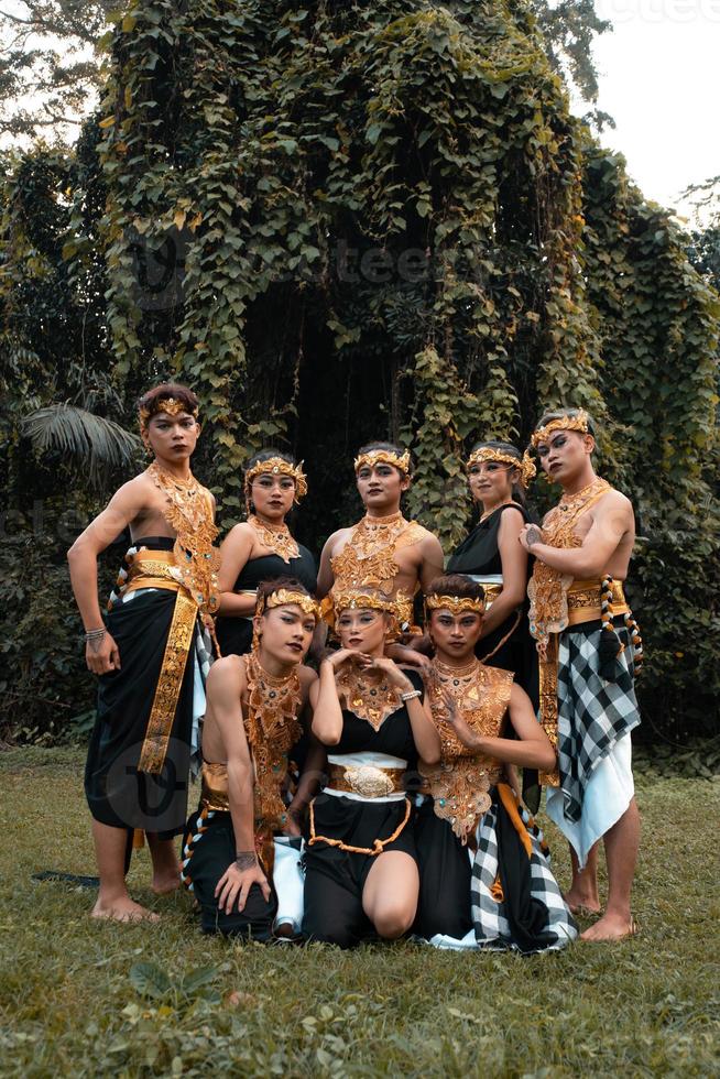 un' gruppo di balinese persone pose insieme con un' contento viso mentre indossare d'oro costumi dopo il prestazione foto