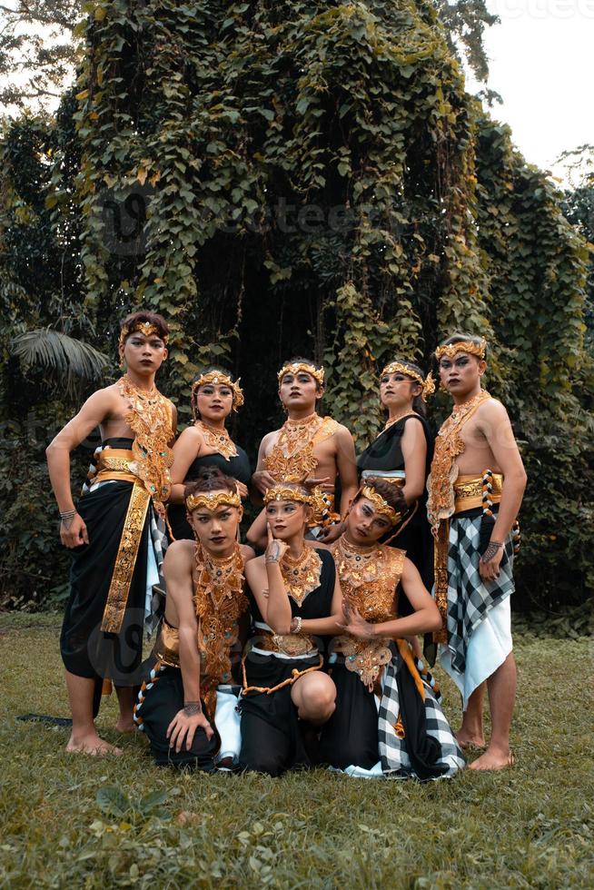 un' gruppo di balinese persone pose insieme con un' contento viso mentre indossare d'oro costumi dopo il prestazione foto