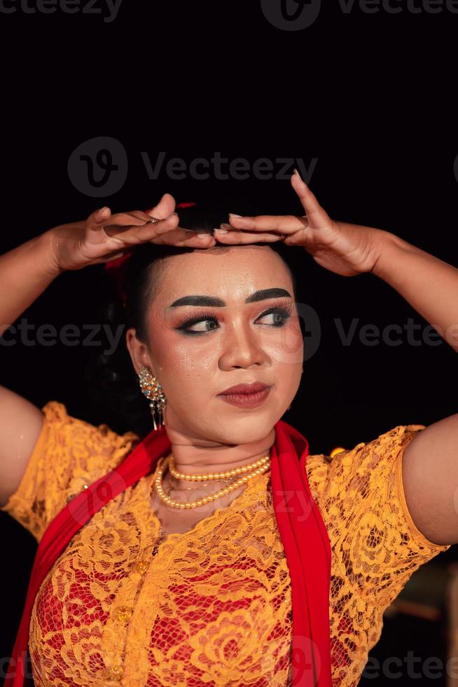 avvicinamento viso di un indonesiano donna con trucco e un arancia vestito mentre indossare un' pezzo di oro gioielleria su sua collo foto