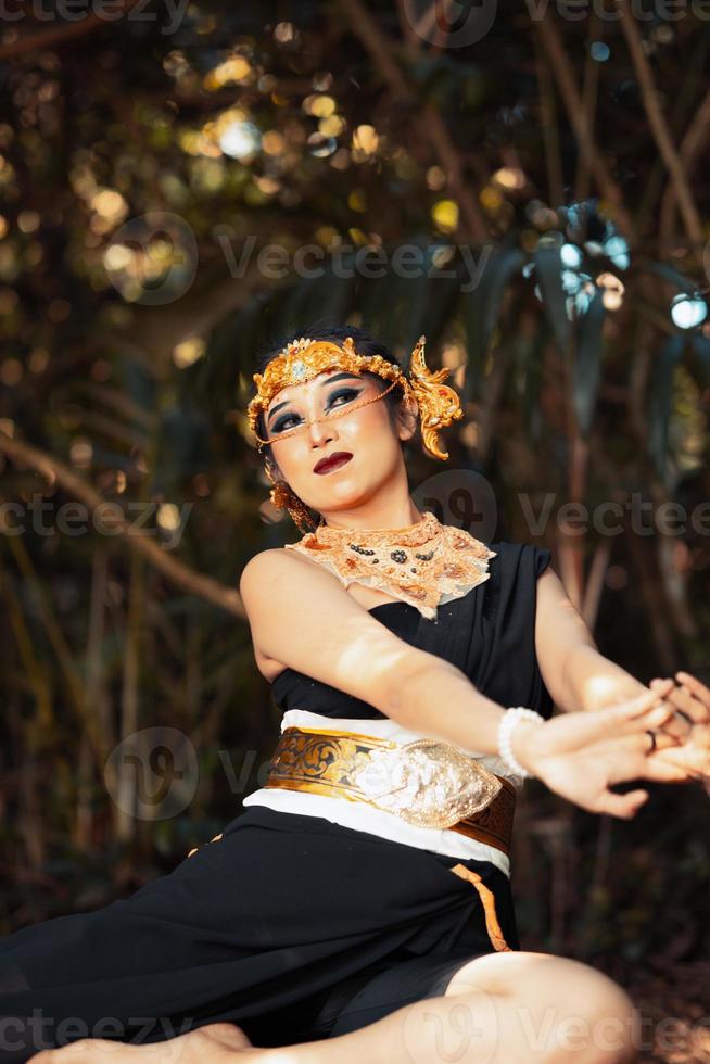 giavanese donna con d'oro corona e nero costume chilling dentro il foresta mentre indossare trucco foto