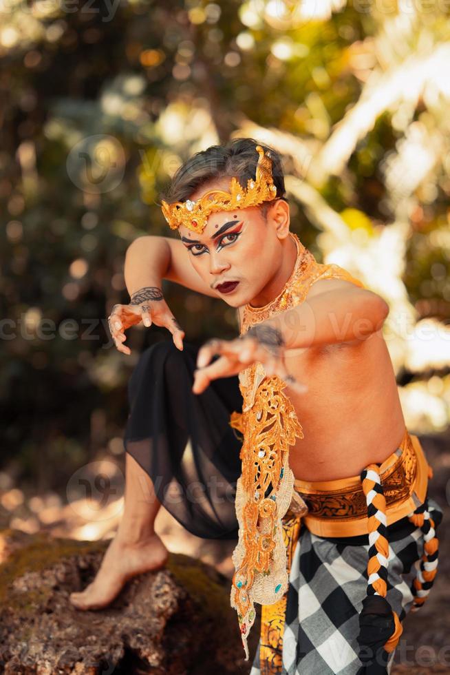 indonesiano uomo danza con il d'oro corona mentre indossare A petto nudo d'oro Abiti su il suo corpo foto
