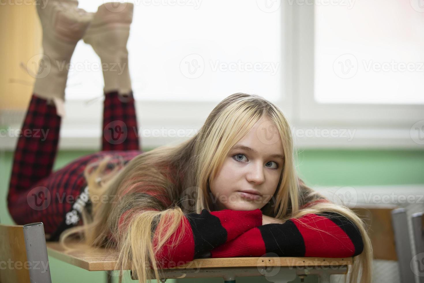 un' adolescenziale ragazza bugie su un' scuola scrivania. alto scuola alunno. quindici anno vecchio ragazza. foto