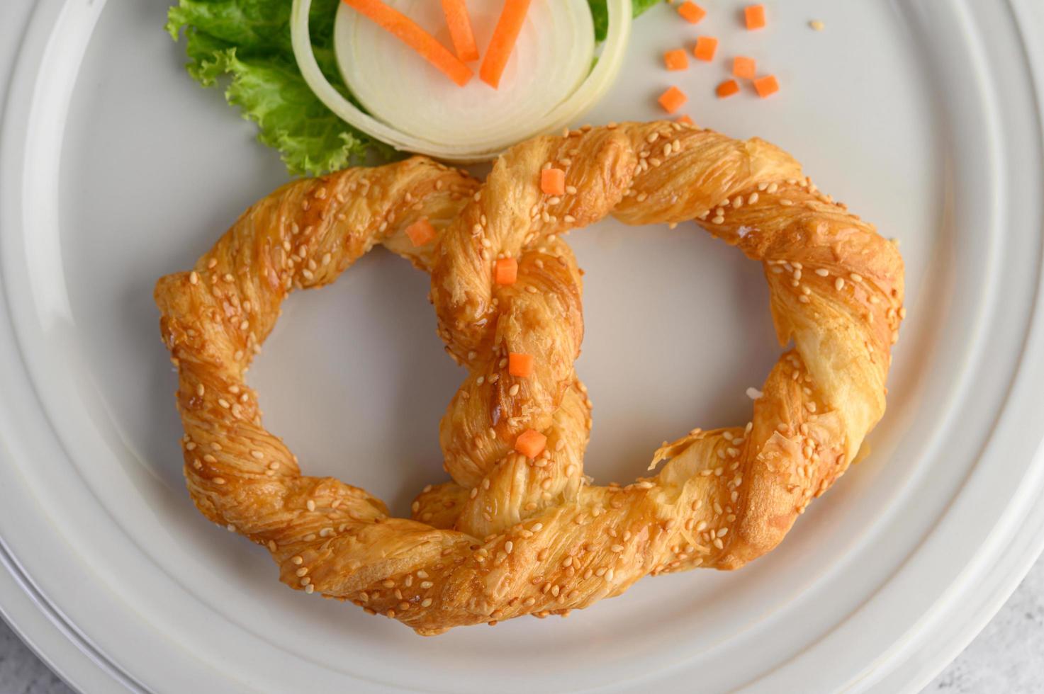 pretzel su un piatto bianco con lattuga e carote foto