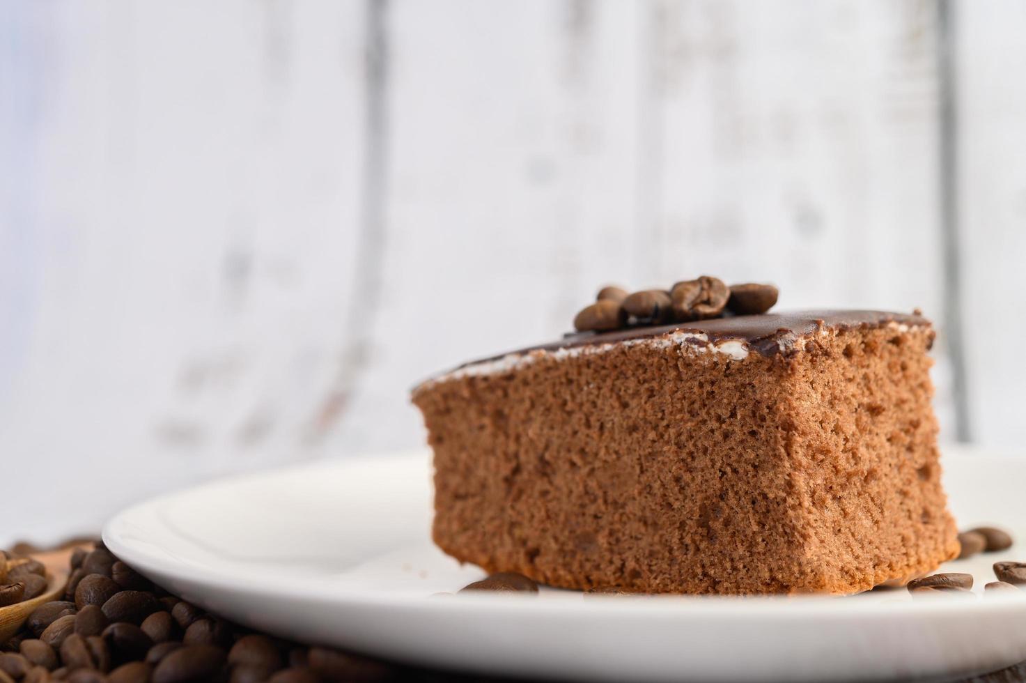 torta al cioccolato su un piatto bianco e un tavolo in legno bianco foto