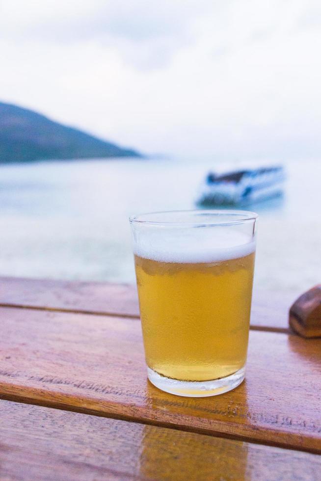 bicchiere di birra sul tavolo vicino alla spiaggia foto