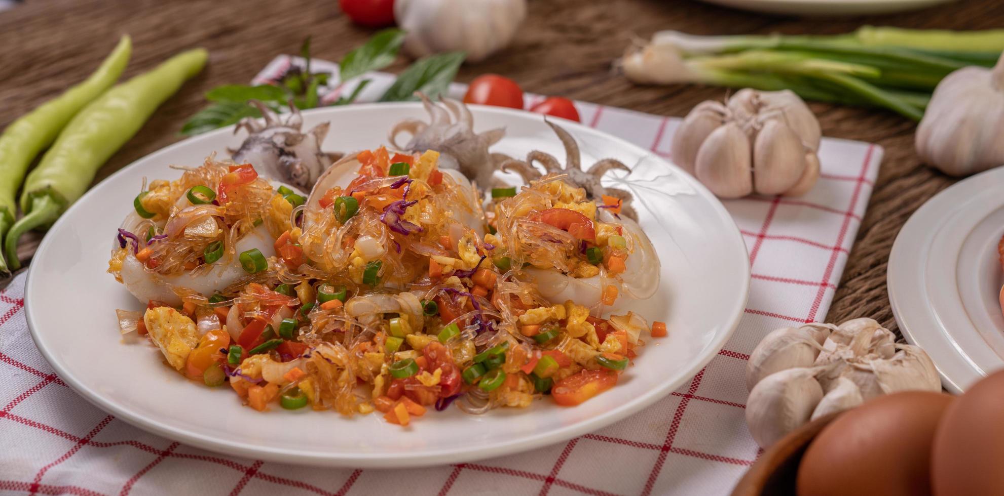 mescolare tagliatelle di vetro fritte con calamari su un panno bianco e rosso foto