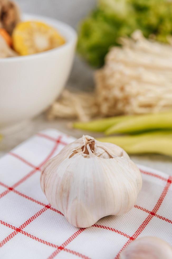 una testa d'aglio posta su un panno bianco e rosso foto