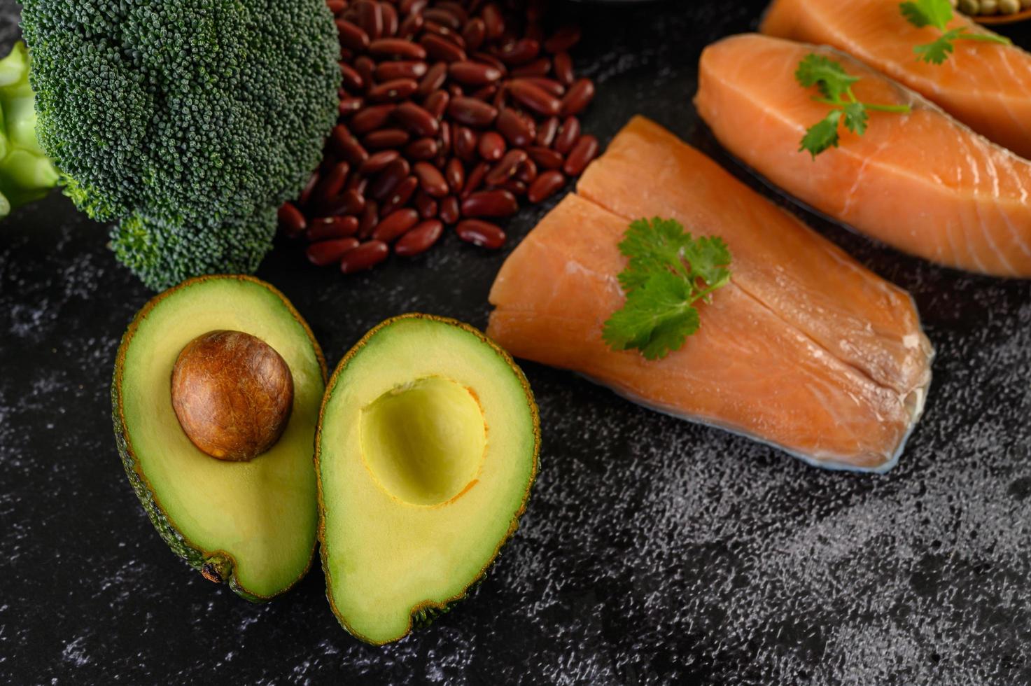 legumi, broccoli, frutta e salmone su uno sfondo di cemento nero foto