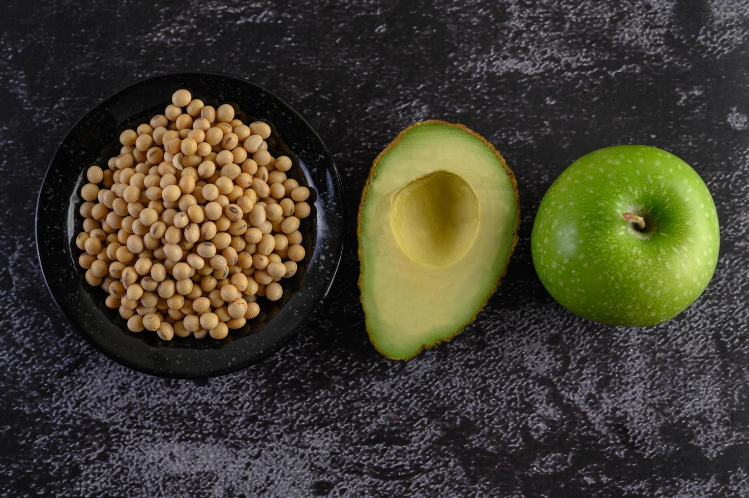 avocado, mela e soia su sfondo di cemento nero foto