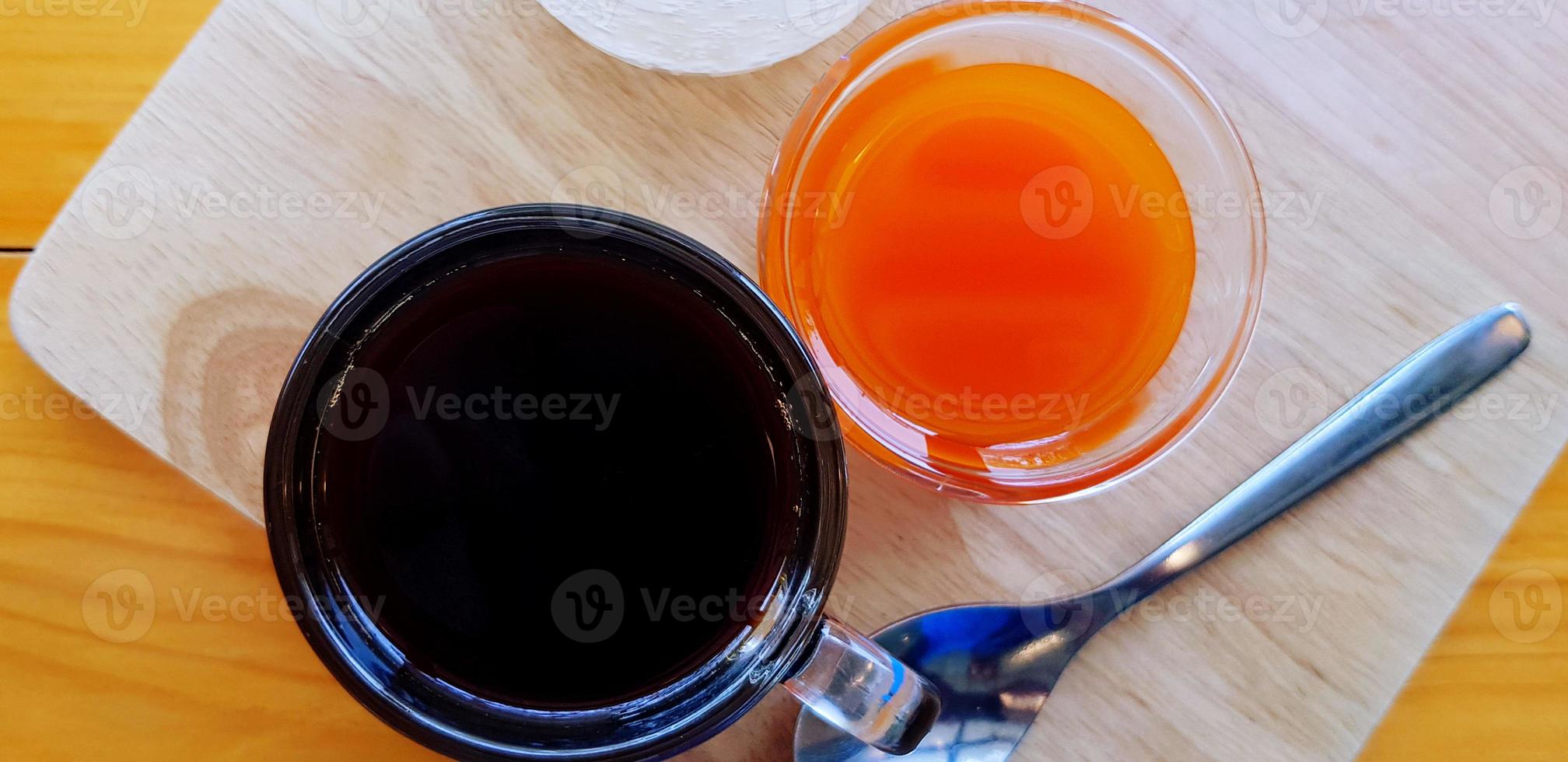 superiore Visualizza di buio caffè espresso tiro con bicchiere di arancia succo e tè cucchiaio su di legno vassoio per servendo cliente nel mattina a caffè bar. rinfresco potabile concep foto