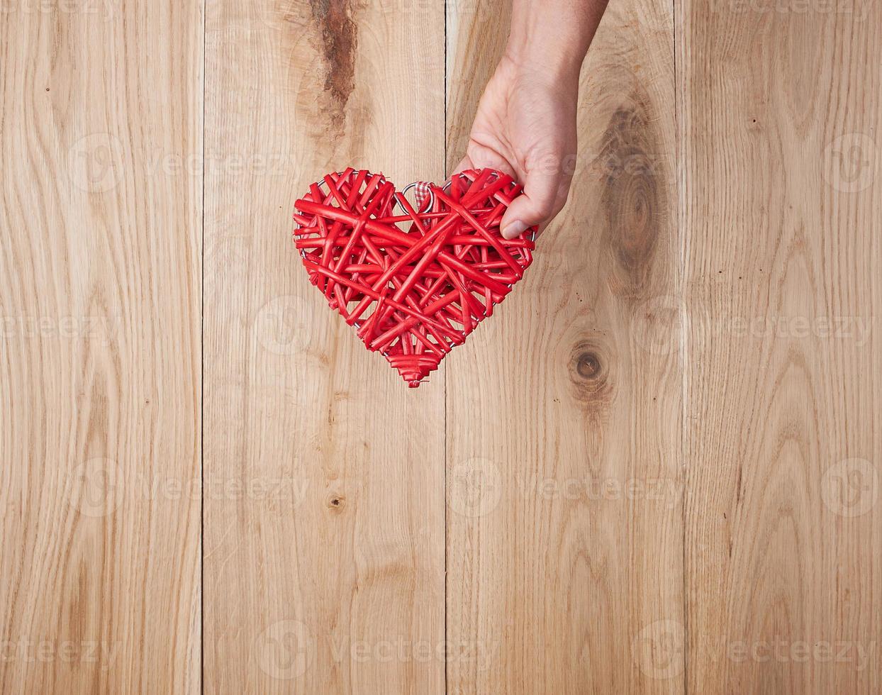 rosso cuore nel umano mano su giallo di legno sfondo foto