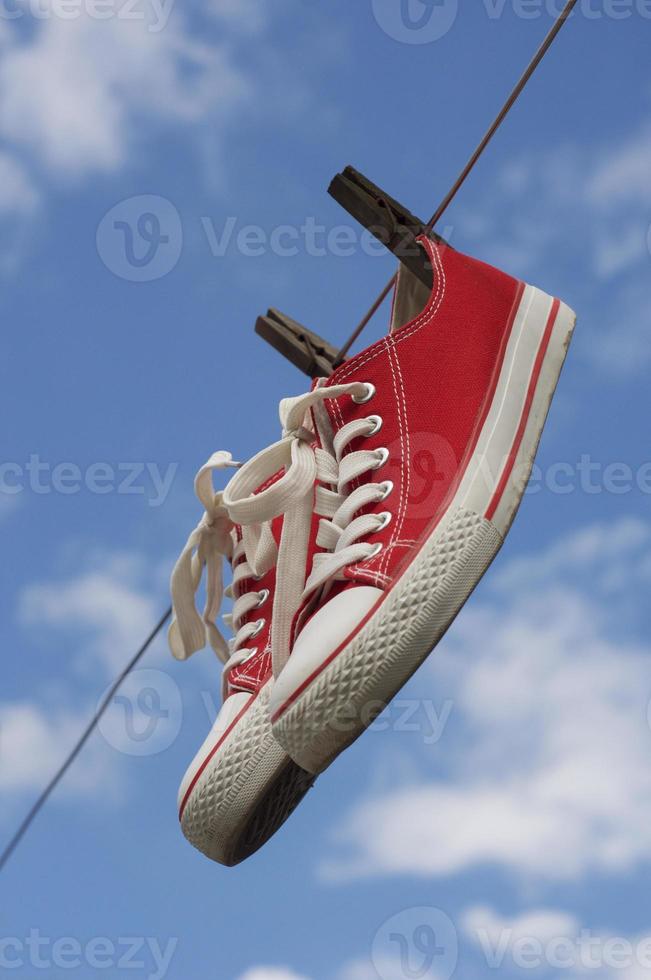 paio di rosso scarpe da ginnastica sospeso su clothesline foto