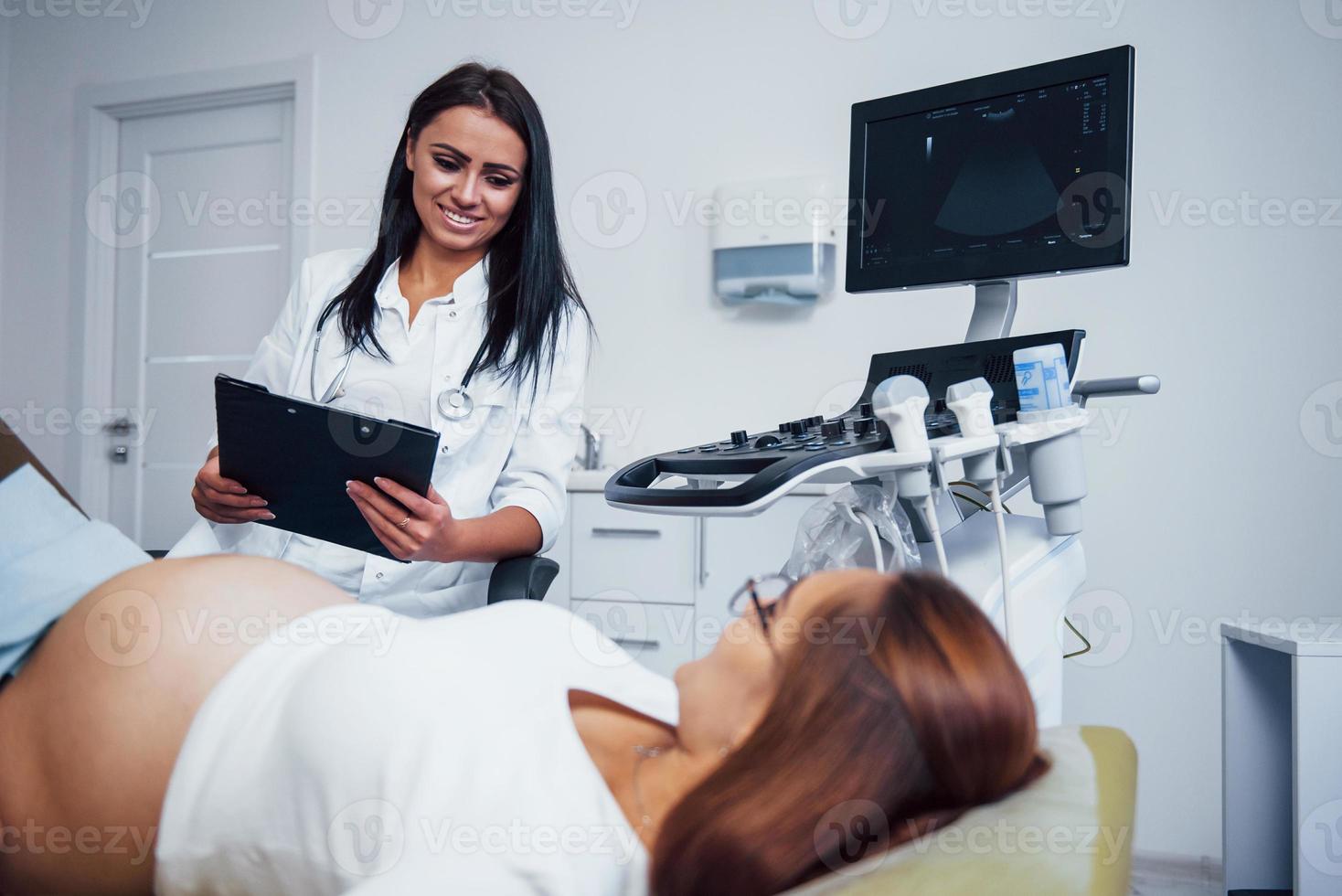femmina medico parla di risultati di ultrasuono per un' incinta donna nel il ospedale foto