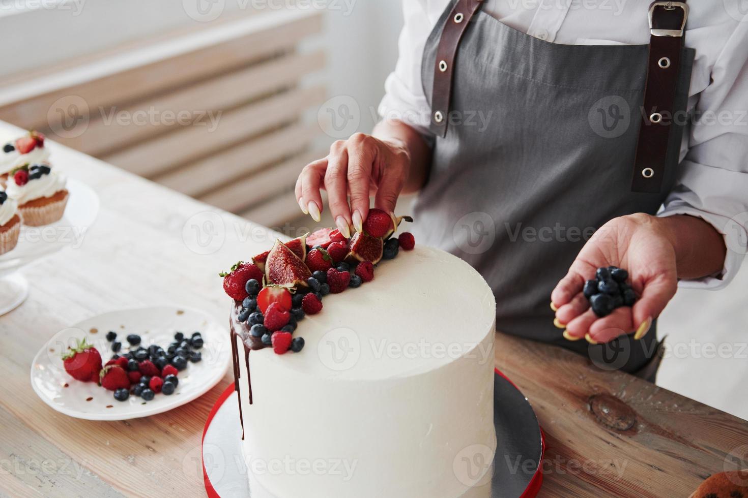 vicino su Visualizza di donna quello mette ciliegie su il dolce torta foto