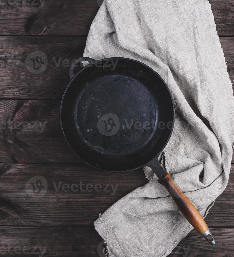 vuoto nero il giro frittura padella con di legno maniglia e grigio biancheria cucina tovagliolo foto