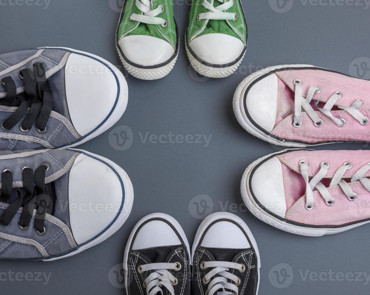 quattro coppie di vecchio tessile scarpe da ginnastica su un' nero sfondo foto