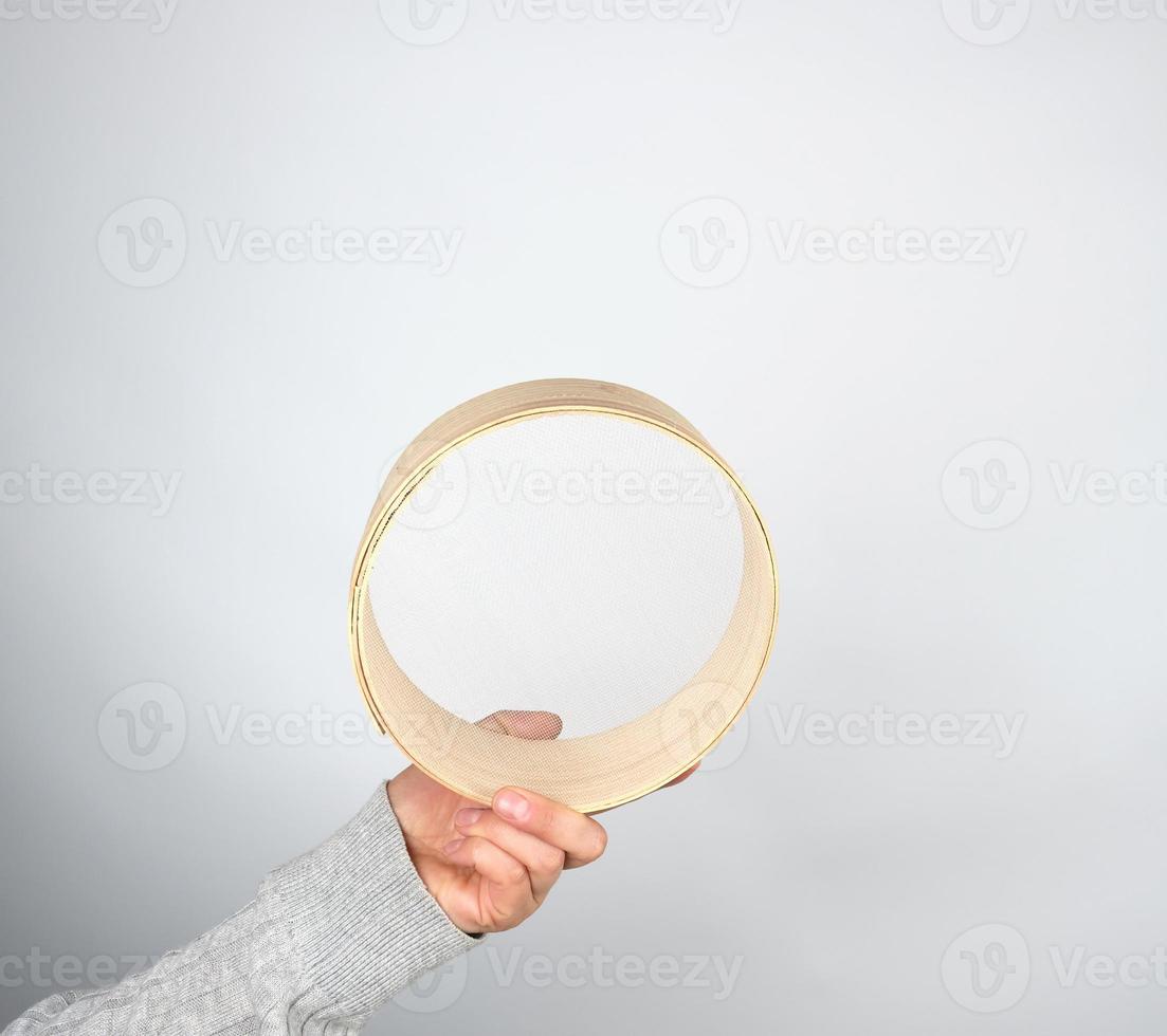 femmina mani hold il giro di legno setaccio per Farina foto