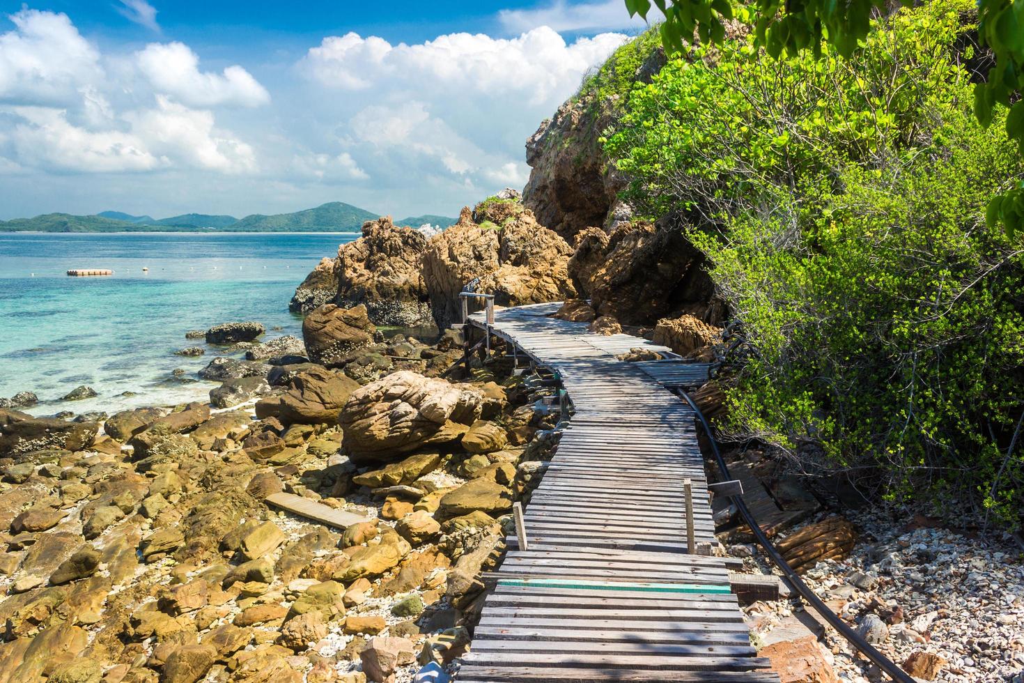 isola tropicale rock e ponte di legno sulla spiaggia con cielo blu nuvoloso foto