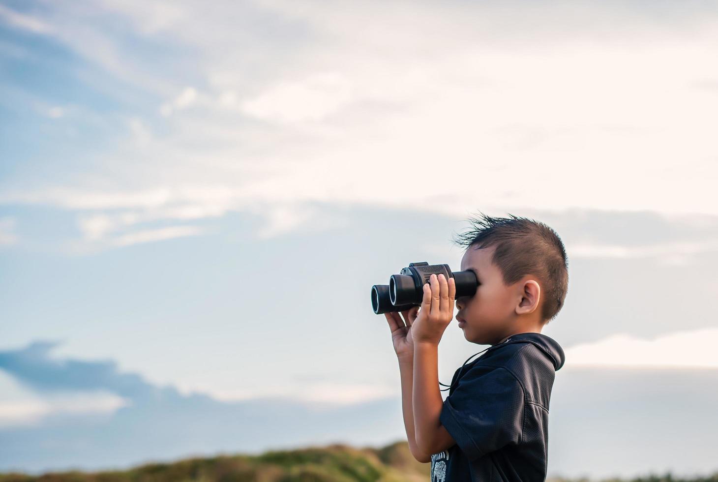 bambino felice che gioca con il binocolo nel prato foto