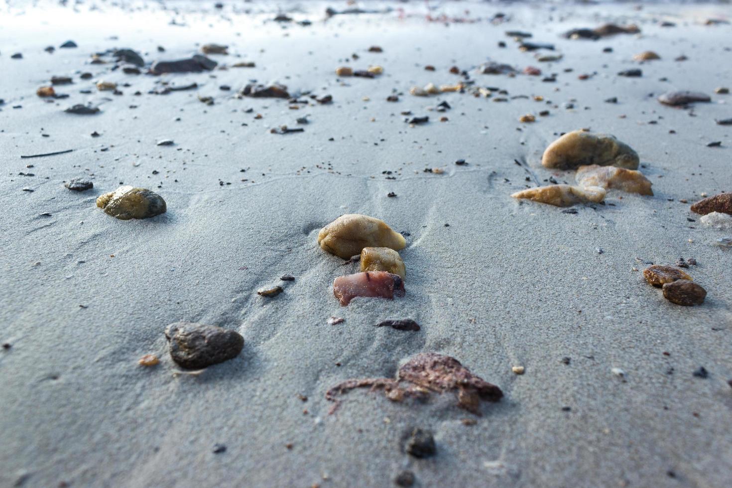 ciottoli sulla sabbia grigia in spiaggia foto