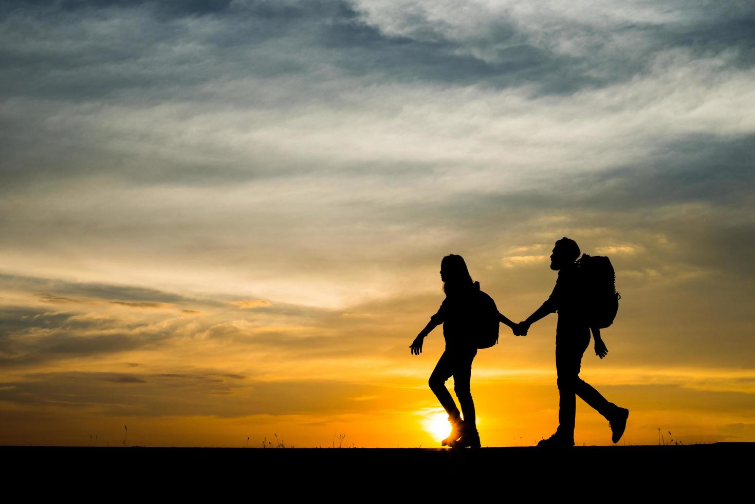 sagome di due escursionisti con zaini che si godono il tramonto foto