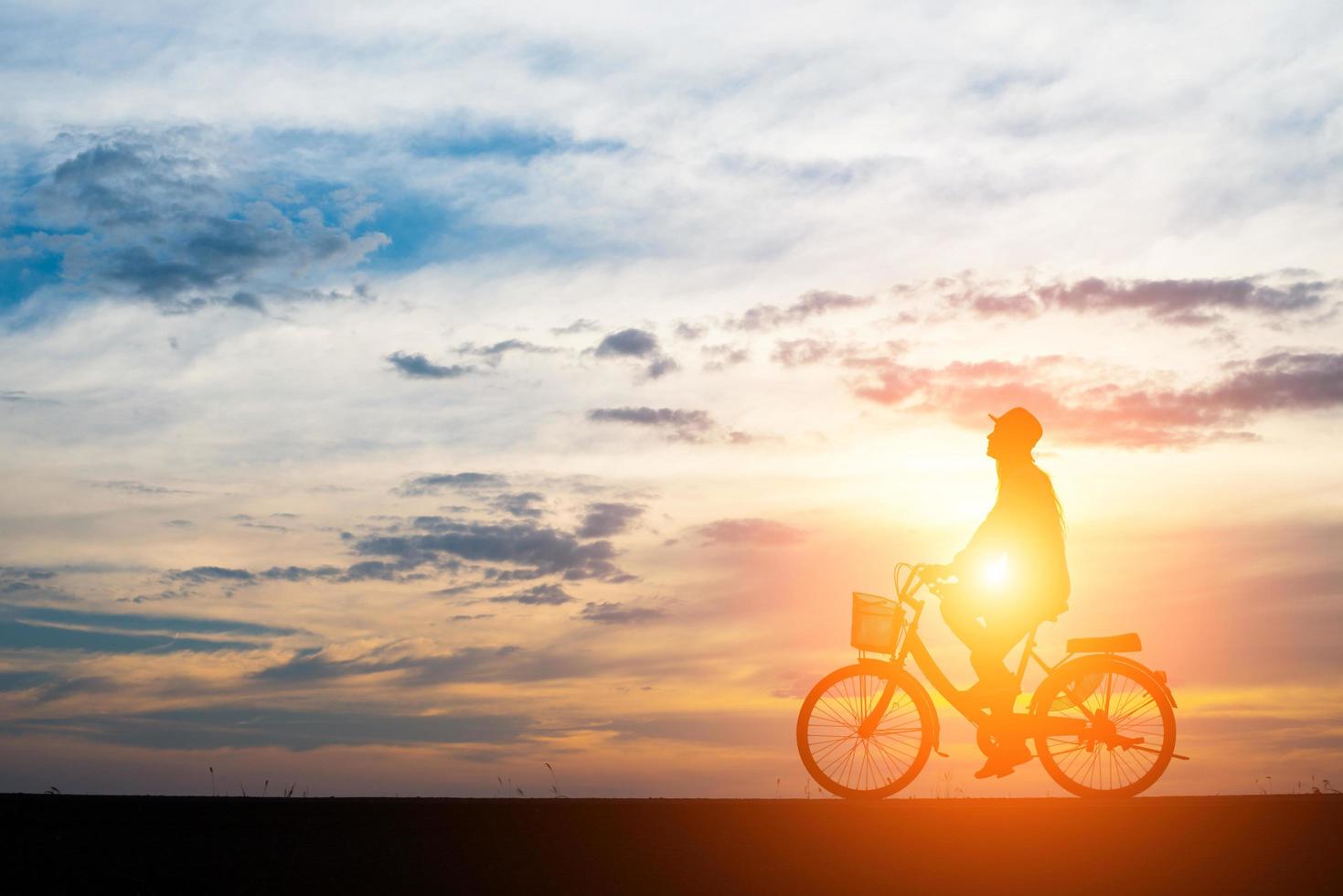 giovane cavalca una bicicletta su sfondo tramonto foto