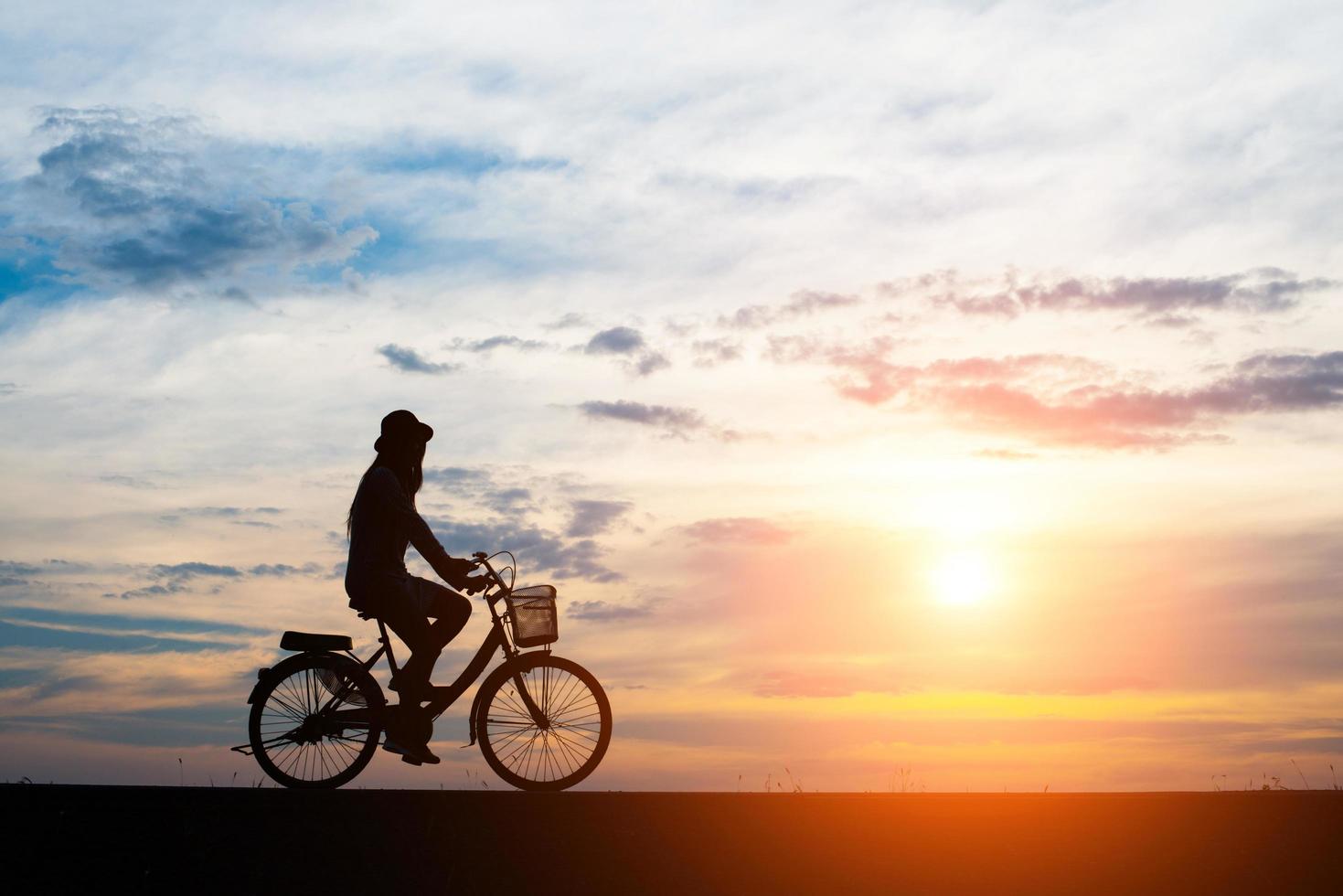 giovane cavalca una bicicletta su sfondo tramonto foto