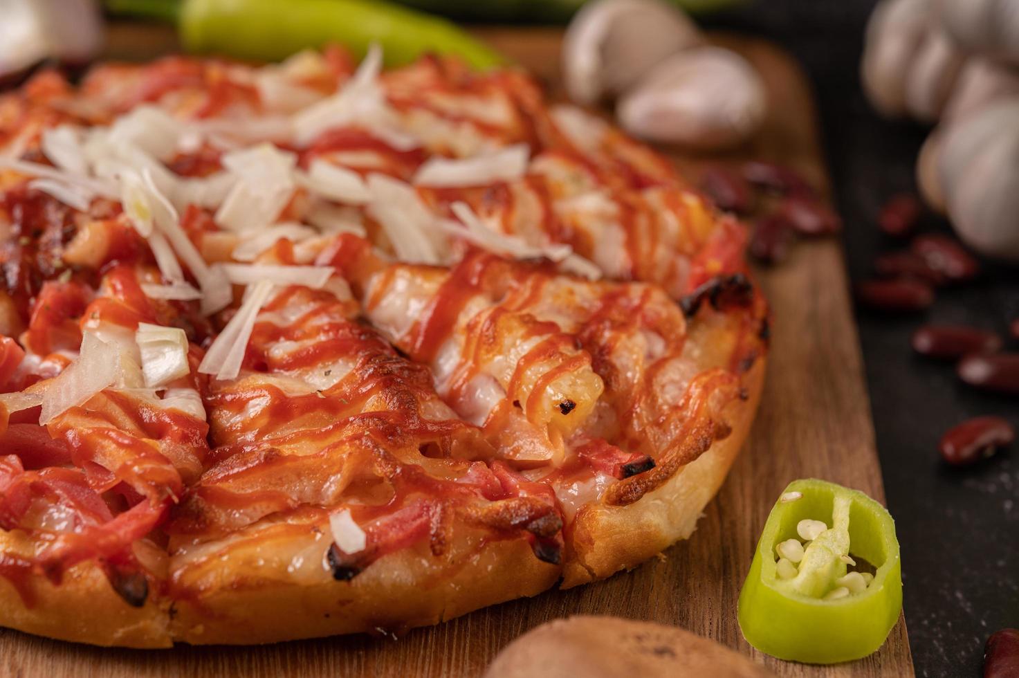 pizza su una tavola di legno con peperoni, aglio, peperoncino e funghi shiitake foto