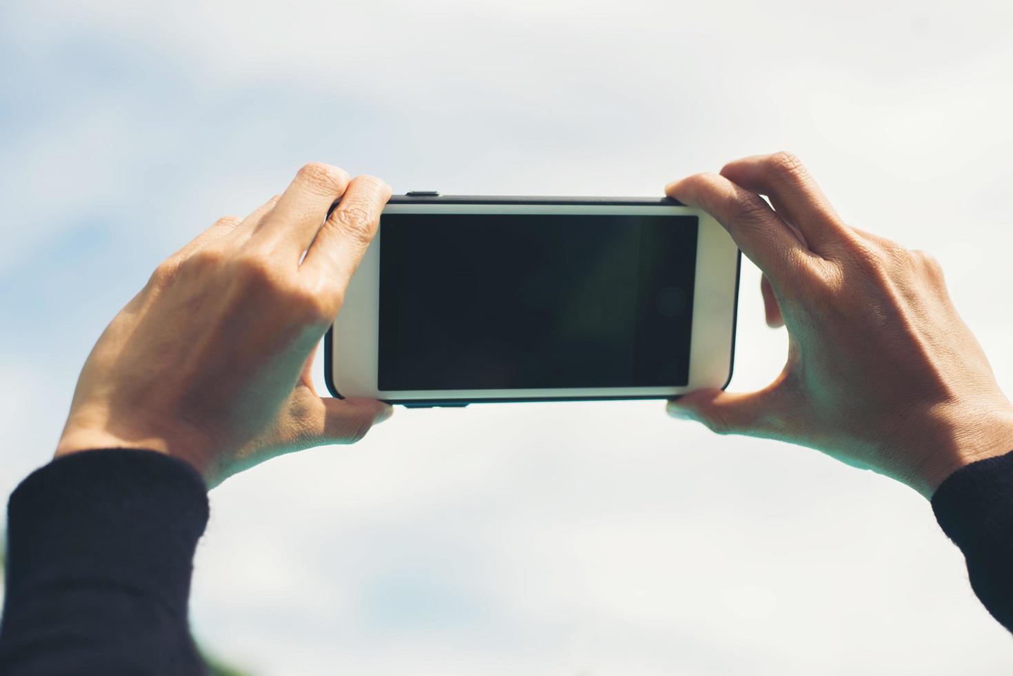 mani femminili che prendono foto con uno smartphone, vista del cielo blu e nuvole