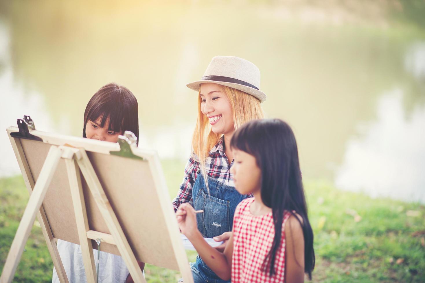 madre e figlie che disegnano immagini insieme in un parco foto