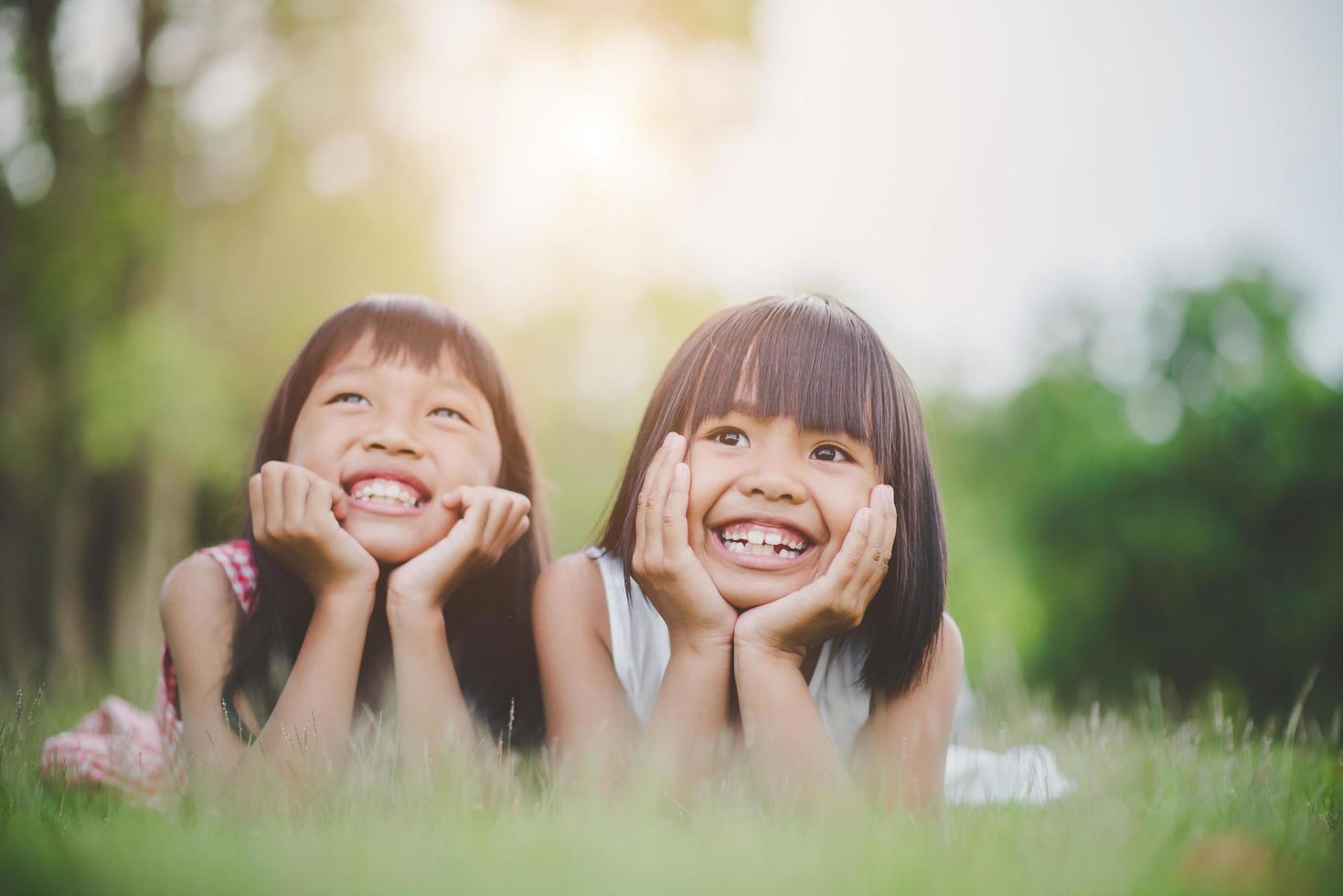 bambine comodamente sdraiate sull'erba e sorridenti foto