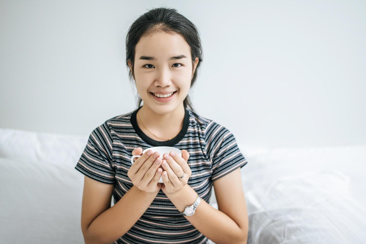 giovane donna con una tazza di caffè a letto foto