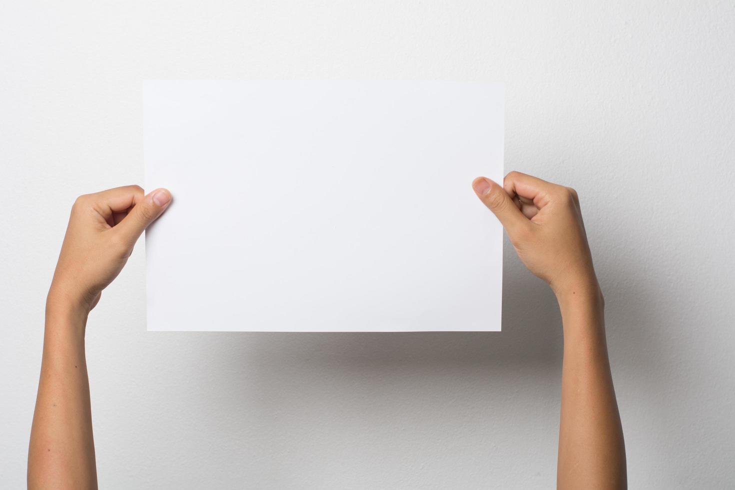 primo piano della mano di una donna che tiene carta bianca isolato su sfondo bianco foto