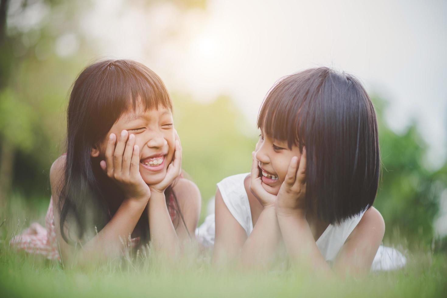 bambine comodamente sdraiate sull'erba e sorridenti foto