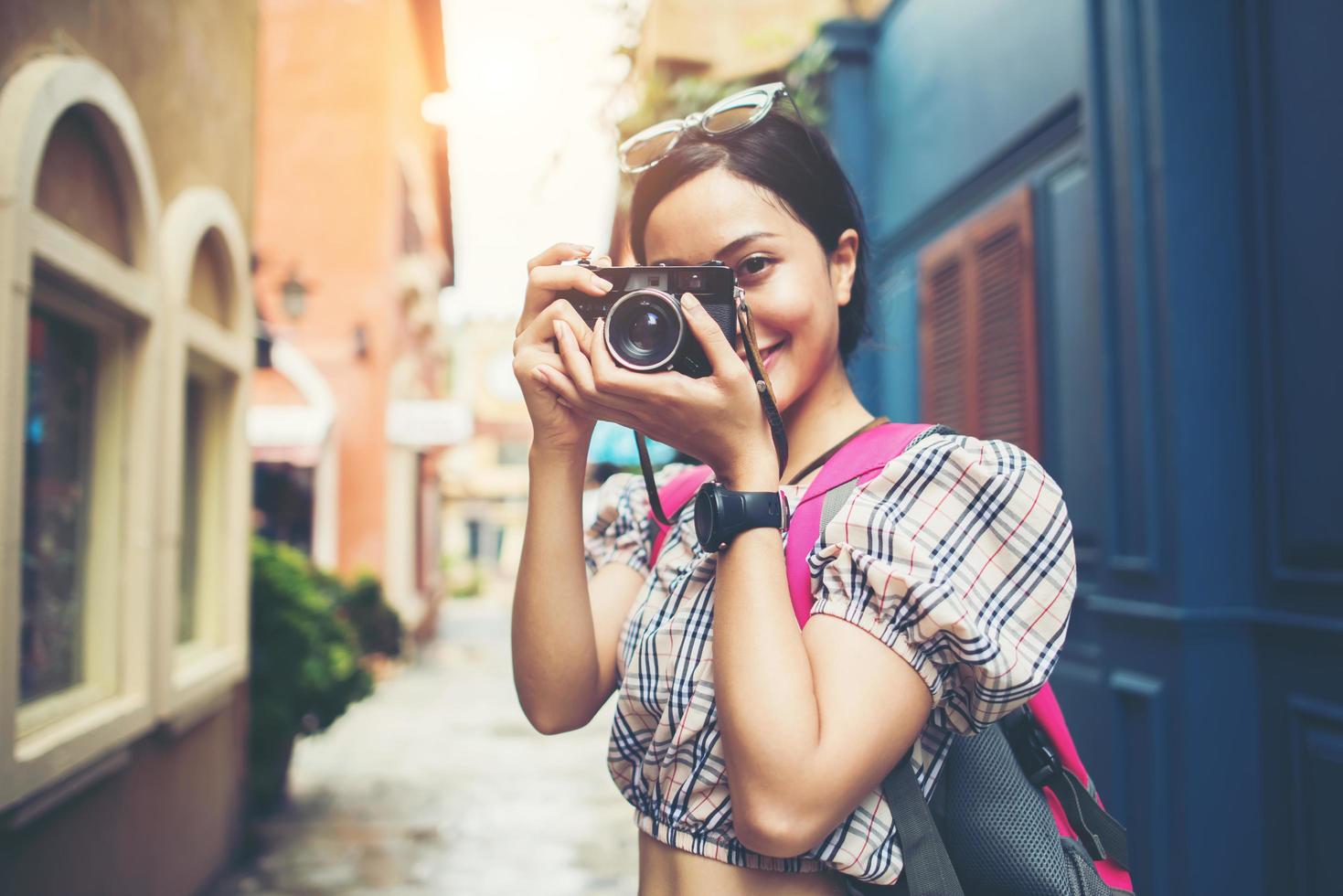 primo piano di una donna giovane hipster in viaggio e scattare foto con la sua macchina fotografica