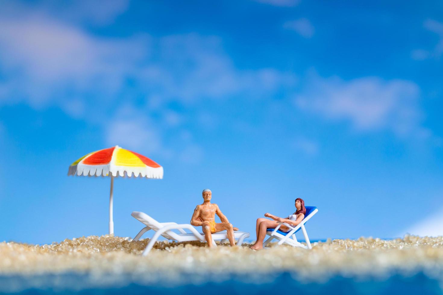 persone in miniatura che prendono il sole sulla spiaggia foto