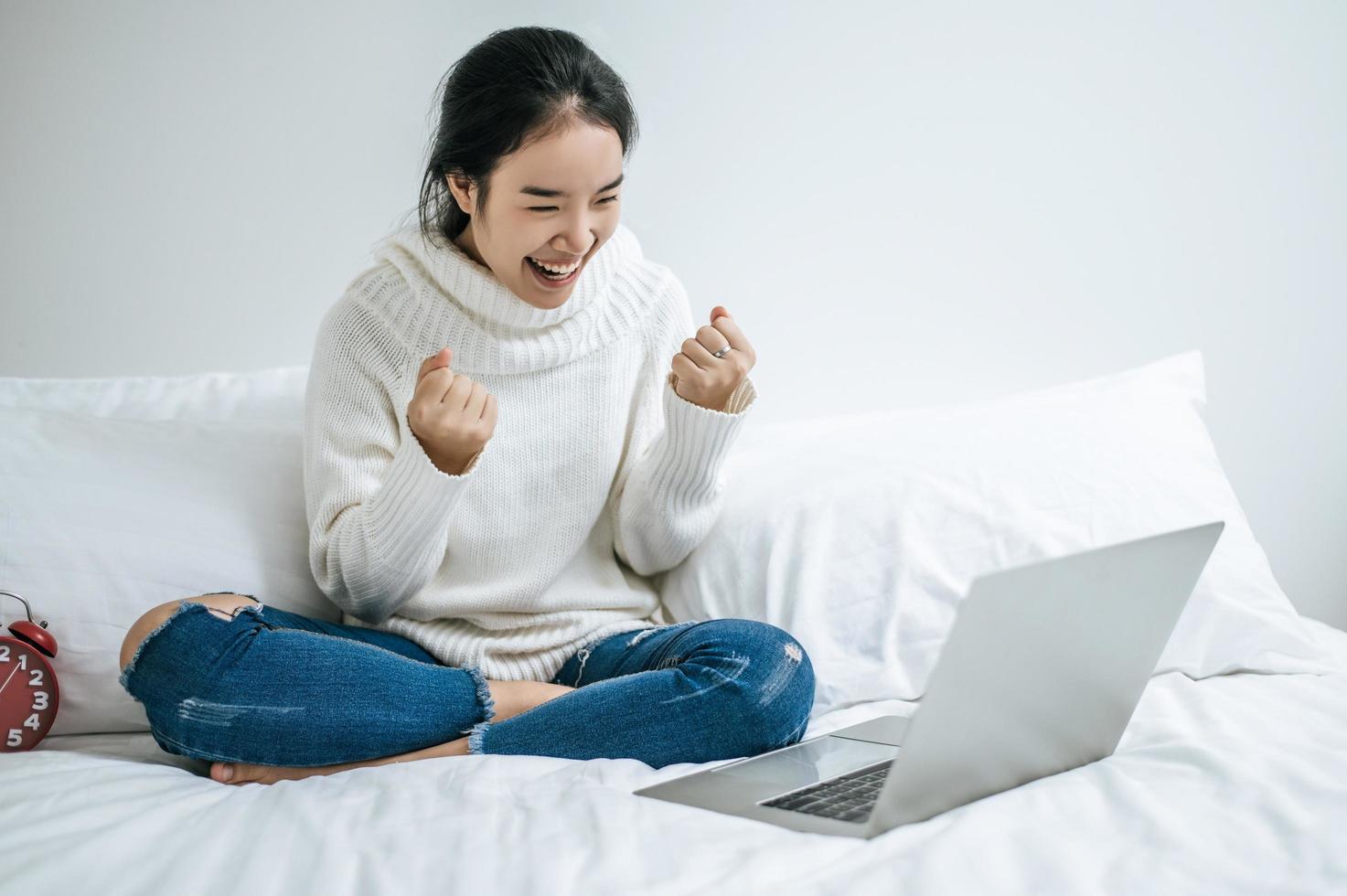 una giovane donna che gioca felicemente sul suo laptop foto