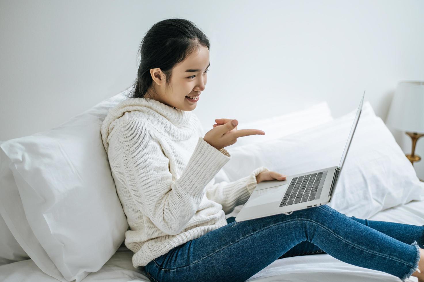 una giovane donna che gioca felicemente sul suo laptop foto